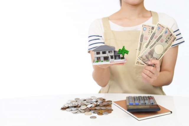 住宅模型と紙幣を持つ女性